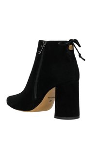 Stivale alla caviglia in suede nero con punta arrotondata, chiusura a zip e tacco largo. Presenta un fiocco decorativo sul retro. Etichetta della misura: 36.