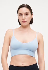 Bralette court côtelé bleu clair avec fines bretelles et un décolleté en V, présentant une texture lisse et une silhouette ajustée.