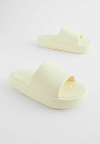 Des sandales jaunes à enfiler avec un dessus en caoutchouc lisse, une large bride et une semelle texturée pour une meilleure adhérence. Design minimaliste avec logo en relief.