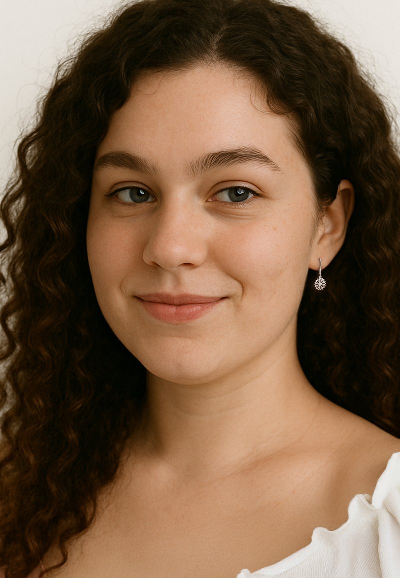 Silverdropörhängen med blommönster, bärs av en person med mörkt, vågigt hår, mot en ljus bakgrund.