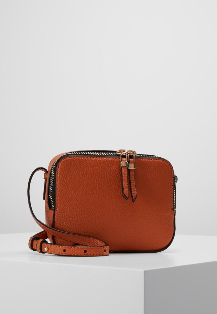 Borsa a tracolla in pelle arancione con chiusura a zip, doppie cerniere e tracolla removibile. Superficie testurizzata con bordatura nera.