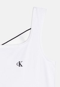 Camiseta sin mangas blanca hecha de algodón suave, con un logo negro "cK" y un ribete negro en contraste a lo largo del cuello interior.