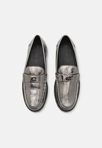 Metallische zilveren leren instappers met een stikselontwerp, voorzien van een logo-accent en een zwarte rubberen zool. Glad oppervlak met glanzende afwerking.