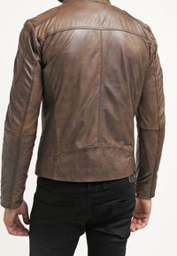 Brun läderjacka med en figursydd design, som har texturerade detaljer, synliga sömmar och en hög krage. Bakifrån visas slanka linjer.