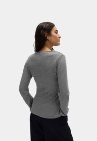 Dopasowany, długorękawowy top z przyjemnej w dotyku szarej tkaniny, z okrągłym dekoltem i delikatnymi przeszyciami na plecach.