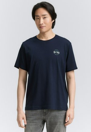 Marineblaue Baumwoll-T-Shirt mit Rundhalsausschnitt und kurzen Ärmeln, mit einem kleinen runden grafischen Logo auf der linken Brust.