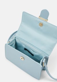 Světle modrá crossbody taška s hladkým povrchem, zlatým uzávěrem a jednou přihrádkou, uvnitř s označením.