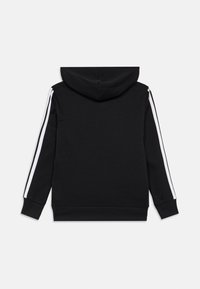 Μαύρη φούτερ με μπούστο, τσέπη μπροστά, κουκούλα και άσπρες λωρίδες κατά μήκος των μανικιών. Φτιαγμένη από μαλακό, υφασμάτινο υλικό.