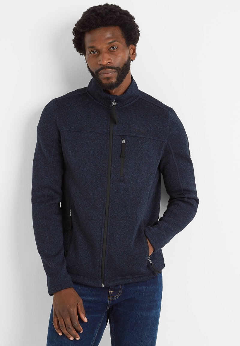 Navy blue fleece jacket with a high collar, front zipper, and two side pockets. Features a textured fabric and minimalistic black accents.