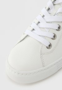 Baskets en cuir blanc avec une finition texturée, dotées de lacets plats blancs, d'œillets argentés et d'une semelle en caoutchouc cousue.