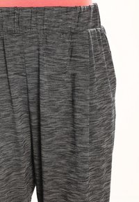 Grau melierte elastische Bundhose mit seitlichen Taschen, getragen von einer Person in einem pinken Oberteil, von der Taille bis zur Mitte des Oberschenkels gezeigt.