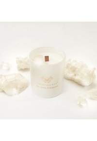 Biała świeca w matowym szklanym pojemniku z drewnianym knotem, opisana jako "CRYSTALLOVE" złotymi literami. Otoczona kryształami kwarcu.