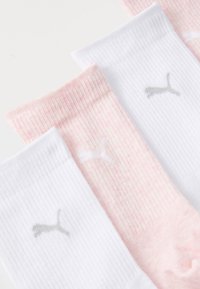 Tre par strumpor: ett par vita med en grå logotyp, två nyanser av rosa med ett subtilt melerat mönster, som har ribbat textil vid mudden.