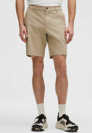 Pantaloncini beige con davanti piatto, chiusura con zip e bottone. Realizzati in materiale leggero, con tasche laterali e vestibilità sartoriale.