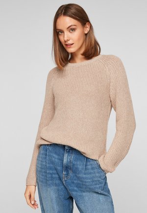 Beige gebreide trui met een textuurafwerking, ronde halslijn en lange mouwen, gecombineerd met blauwe high-waisted jeans.
