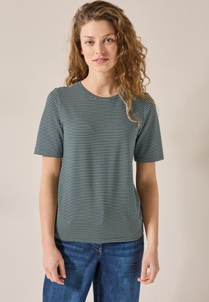 Camiseta de manga corta y cuello redondo en verde oscuro con rayas blancas horizontales. Tejido suave y texturizado con un corte relajado, combinada con jeans azules.
