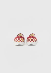 Red canvas slip-on shoes with a checkerboard pattern in yellow and white. White rubber soles and logo tag on the heel.