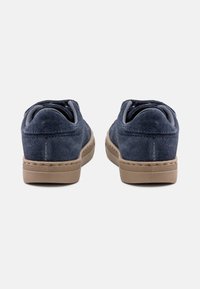 Navy suede sneakers with rounded backs and beige rubber soles, featuring subtle stitching and a textured surface.