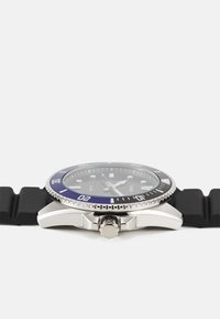 Montre en acier inoxydable argenté avec une lunette bleue, un bracelet en caoutchouc noir et un cadran rond noir avec des index et des aiguilles argentés.