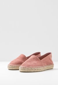 Espadrilles en tissu rose avec un bout arrondi, des ouvertures sur les côtés élastiques et des semelles en jute tressé. Texture lisse avec des détails de conception minimaux.