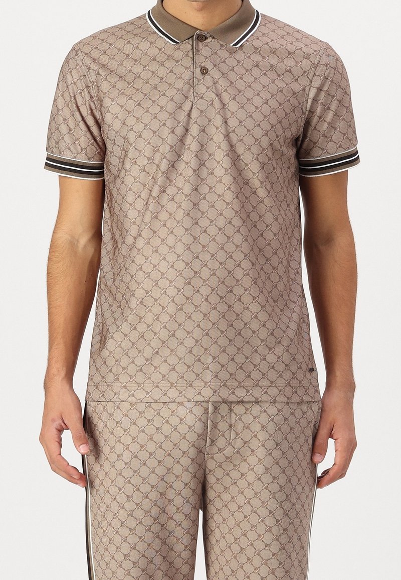 Homme portant un polo beige à motifs et un pantalon assorti avec un col et des poignets rayés marron foncé et blanc.
