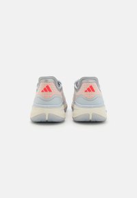 Light gray athletic shoes with pink accents, textured mesh upper, three red stripes on heel, and elastic detail around the collar.