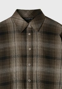 Chemise à carreaux marron et noir à boutons avec col pointu et cinq boutons visibles au centre devant.
