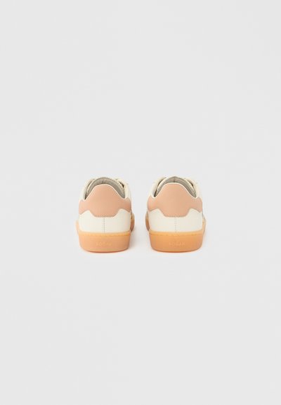 Λευκά και μπεζ αθλητικά παπούτσια με λείο δερμάτινο επάνω μέρος, σκάλιστη λεπτομέρεια φτέρνας σε ανοιχτό καφέ και υφή σόλας από καουτσούκ.