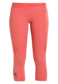 Leggings courts corail rose Adidas avec ceinture élastique et logo Adidas noir près de la cheville gauche.