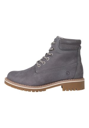 Bottine en cuir gris, à bout rond, avec un laçage sur le devant, des œillets métalliques et une semelle en caoutchouc texturé. Présente un détail cousu et un logo.