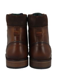 Botas de cuero marrón hasta el tobillo con un acabado liso, detalles de ante en el cuello y un tacón de madera robusto. Mínimos elementos de metal y detalles de diseño.
