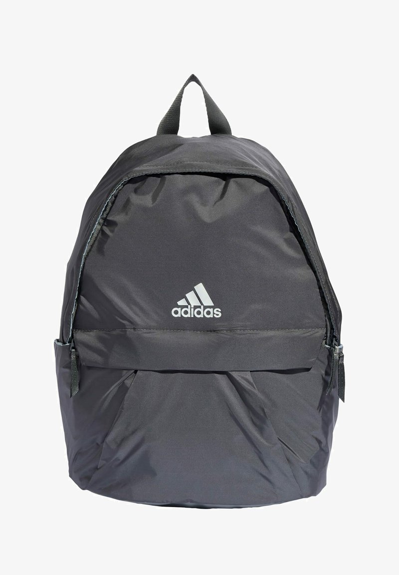 Mochila negra de nailon con forma redondeada, bolsillos con cremallera y una solapa frontal. Presenta el logo de Adidas en blanco y correas de tela.