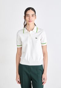 Witte polo-shirt met groene en gele gestreepte kraag en mouwcuppen, voorzien van een klein geborduurd logo op de borst en een geribde zoom.