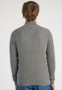 Gray knitted sweater featuring a ribbed texture, high neck, and fitted cuffs. The back view shows a smooth, seamless design transition.