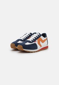 Navyblaue und weiße Sneaker mit orangefarbenen Akzenten, aus Wildleder, mit strukturierter Gummisohle und gesticktem Logo an der Seite.