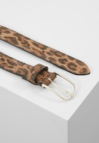Kožený pás s leopardím vzorem a jemnou texturou, s kovovou sponou ve stříbrné barvě a více otvory pro nastavení.