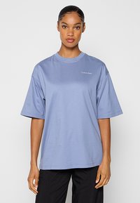 Duża koszulka z krótkim rękawem z jasnoniebieskiej bawełny z okrągłym dekoltem i małym białym logo "Calvin Klein" na górnej lewej stronie klatki piersiowej.