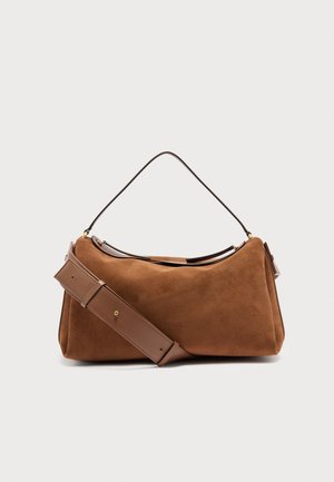 Barna szarvasbőr válltáska állítható bőrszíjjal és ívelt felső fogantyúval, egyszerű világos háttér előtt.