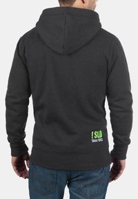 Dark grey hoodie with a hood and kangaroo pocket. Features a graphic in green and white on the lower back. Made of soft, textured fabric.