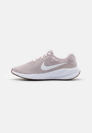 Lyserød Nike løbesko med hvid Swoosh-logo, hvidt polstret mellemsål og brun ydersål, vist fra siden på en hvid baggrund.