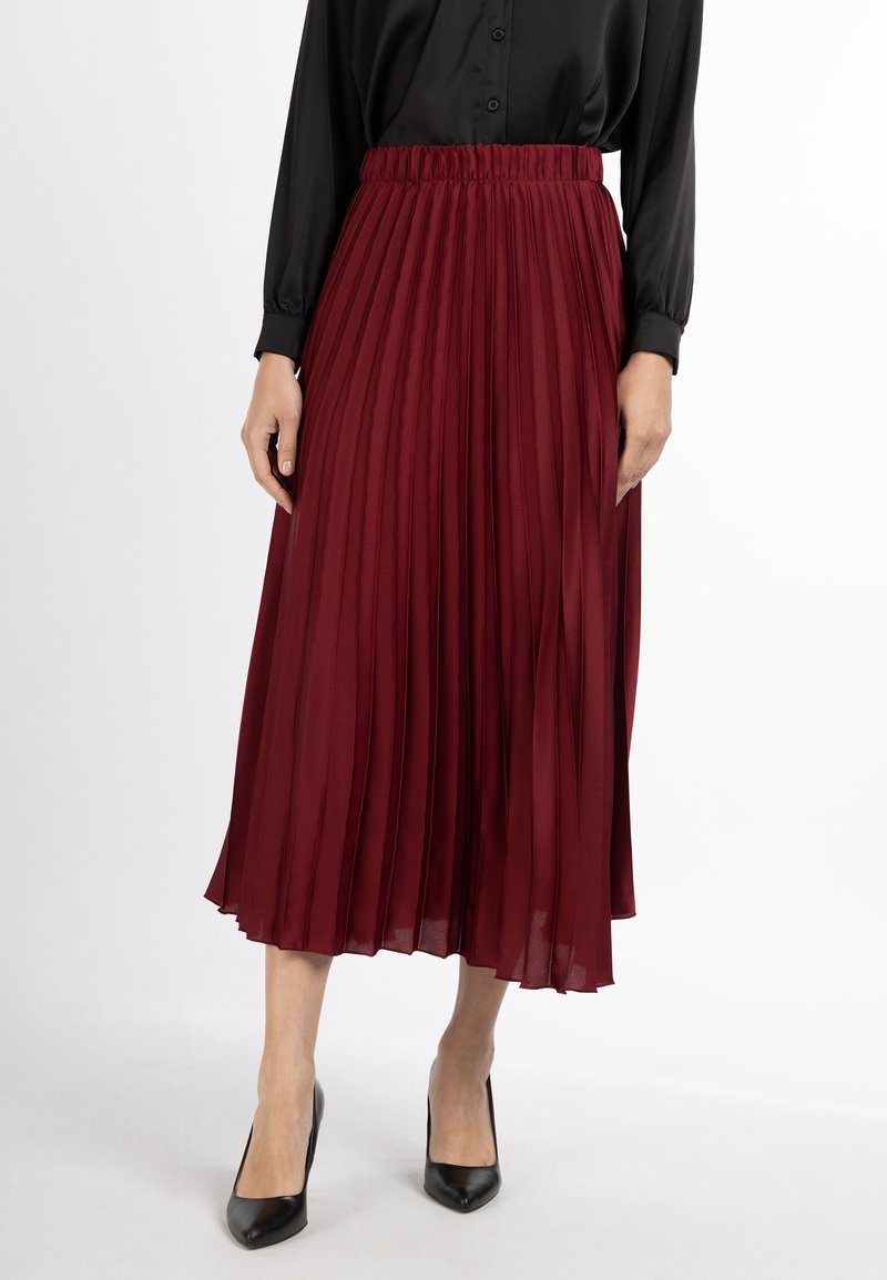 Fustă midi plisată burgundy cu talie elastică, textură de material fluid, asortată cu pantofi cu vârf ascuțit negri.