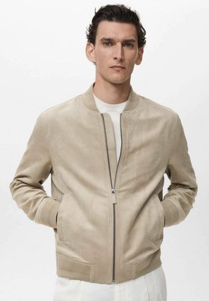 Beige suede bomber jacket with a zip front, ribbed cuffs and hem, and side pockets, featuring minimalistic design and smooth texture.