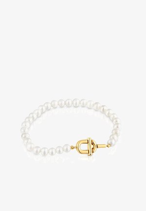 Bracelet avec des perles blanches rondes et un fermoir à bascule en or sur un fond blanc réfléchissant.