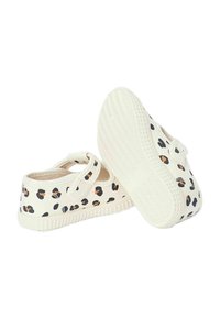 Des chaussures en tissu blanc avec un motif léopard noir et marron, dotées d'une sangle velcro et d'une semelle en caoutchouc texturée.