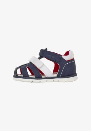 Sandalo per bambini blu e bianco con cinturini in velcro, design aperto, superiore testurizzato, fodera rossa e suola in gomma bianca.