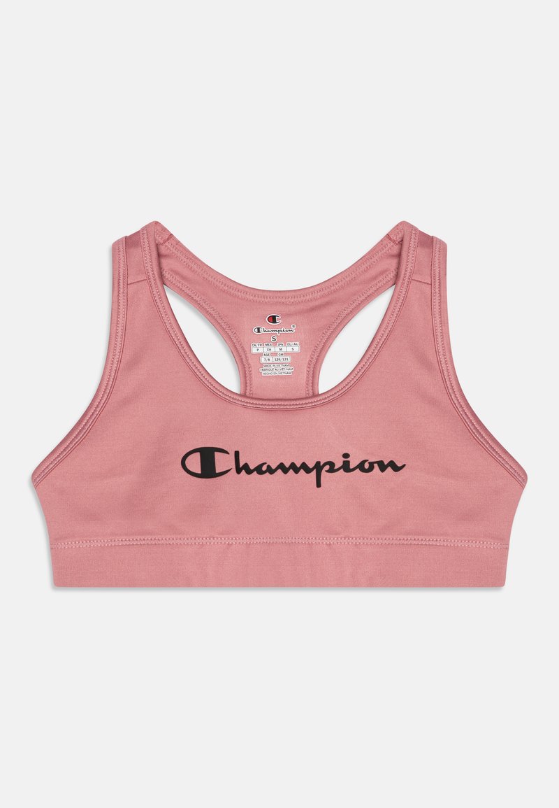 Rozā sporta krūšturis ar gludu tekstūru, ar sacīkšu aizmuguri un izteiksmīgu melnu "Champion" logotipu uz priekša.