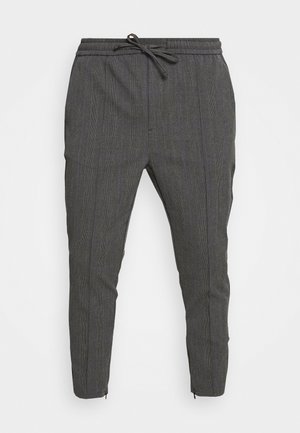 Pantalones ajustados de color gris oscuro con un sutil patrón de cuadros, cintura elástica, cordón de ajuste y cremalleras en los tobillos que realzan el diseño entallado.