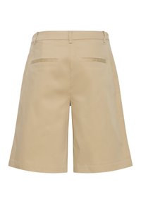 Shorts beige coupés au genou avec passants de ceinture, deux poches passepoilées à l'arrière et une taille épurée et plate.