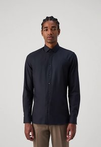 Schwarzes langärmeliges Hemd mit Knopfleiste aus glattem Stoff, mit spitzem Kragen und Standardpassform. Dezenter Glanz, ohne Muster oder Verzierungen.