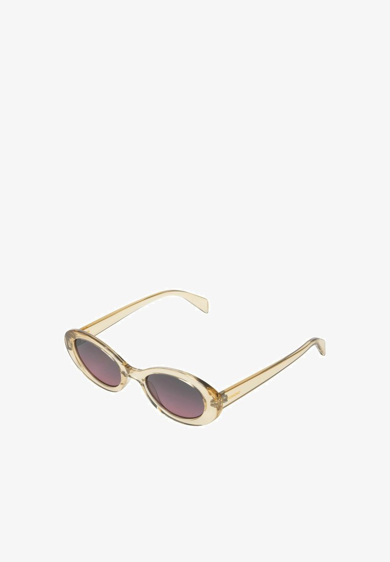 Transparante beige ovalen zonnebrillen met donkergetinte lenzen en slanke pootjes, gekanteld om de voor- en zijkant details te tonen.